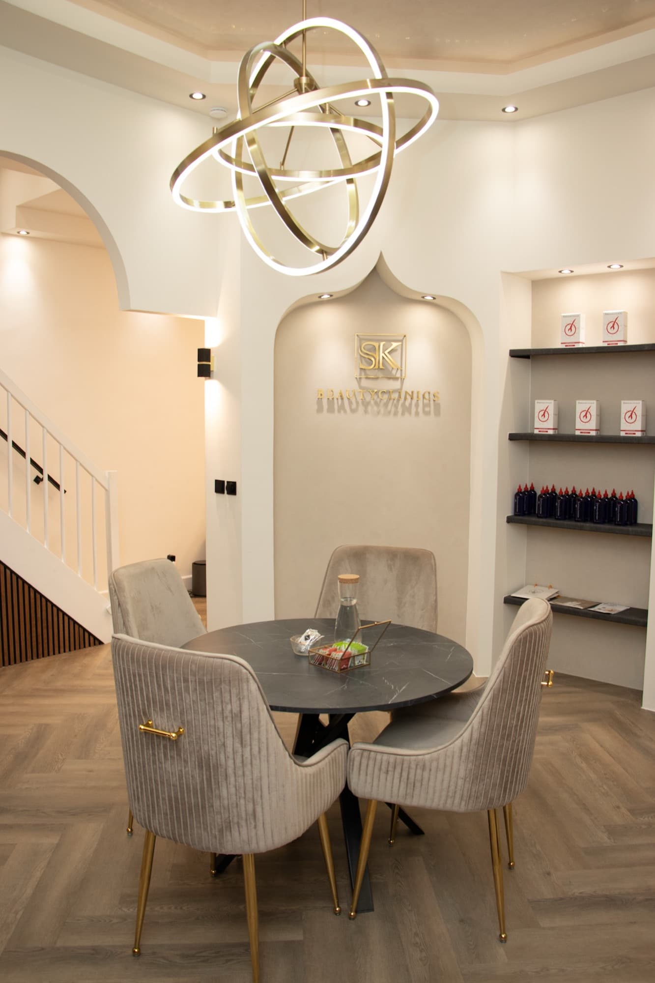 Wachtruimte van SK Beautyclinics met gouden hanglamp en fluwelen stoelen