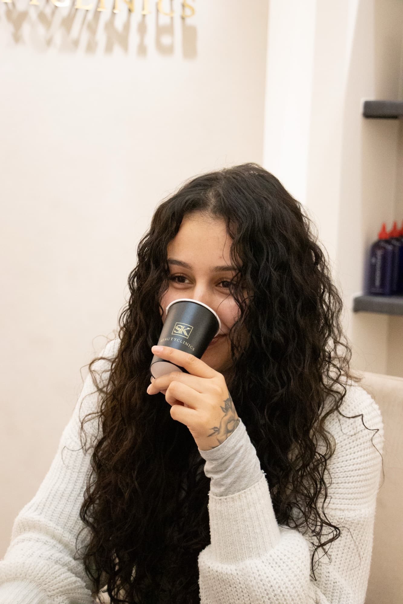 Klant ontspant met een drankje in de rustige sfeer van SK Beautyclinics
